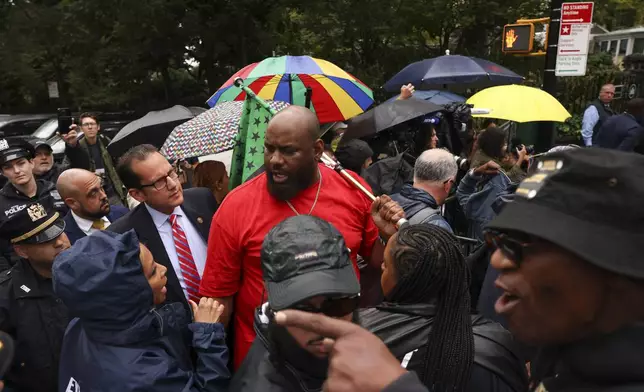 A protestor talks with law enforcement personnel and media while demonstrating against New York City Mayor Eric Adams during a news conference outside Gracie Mansion, Thursday, Sept. 26, 2024, in New York. (AP Photo/Yuki Iwamura)