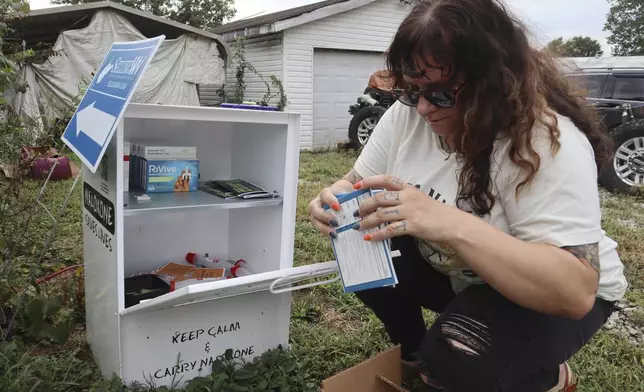 Tasha Withrow, a person in recovery and co-founder of harm reduction organization Project Mayday, refills a new naloxone distribution box in a residental neighborhood of Hurricane, W.Va. on Tuesday, Sept. 24, 2024. (AP Photo/Leah Willingham)