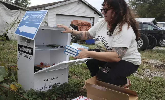 Tasha Withrow, a person in recovery and co-founder of harm reduction organization Project Mayday, refills a new naloxone distribution box in a residental neighborhood of Hurricane, W.Va. on Tuesday, Sept. 24, 2024. (AP Photo/Leah Willingham)