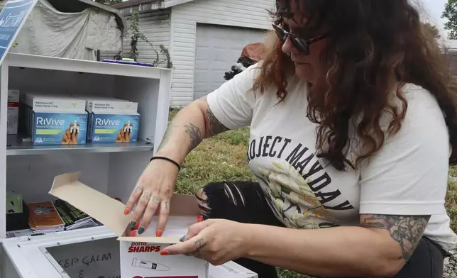 Tasha Withrow, a person in recovery and co-founder of harm reduction organization Project Mayday, refills a new naloxone distribution box in a residential neighborhood of Hurricane, W.Va. on Tuesday, Sept. 24, 2024. (AP Photo/Leah Willingham)