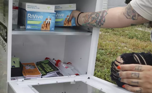 Tasha Withrow, a person in recovery and co-founder of harm reduction organization Project Mayday, refills a new naloxone distribution box in a residental neighborhood of Hurricane, W.Va. on Tuesday, Sept. 24, 2024. (AP Photo/Leah Willingham)