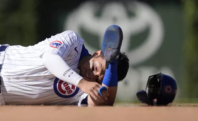 Chicago Cubs Seiya Suzuki lays in the ground after being hit by Washington Nationals catcher Drew Millas' throw to second as Suzuki stole the base during the eighth inning of a baseball game Friday, Sept. 20, 2024, in Chicago. (AP Photo/Charles Rex Arbogast)