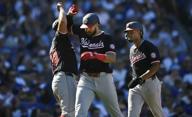 Washington Nationals' Joey Gallo, center, celebrates with teammates Juan Yepez, left, and Jose Tena, right, after hitting a three-run home run during the sixth inning of a baseball game against the Chicago Cubs in Chicago, Saturday, Sept. 21, 2024. (AP Photo/Paul Beaty)