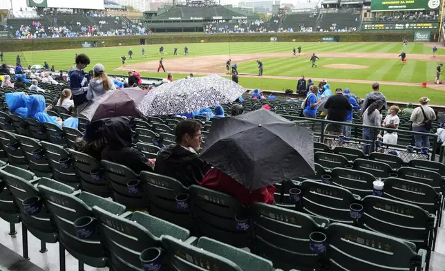 Fans wait during a rain delay before a baseball game between the Washington Nationals and the Chicago Cubs in Chicago, Sunday, Sept. 22, 2024. (AP Photo/Nam Y. Huh)