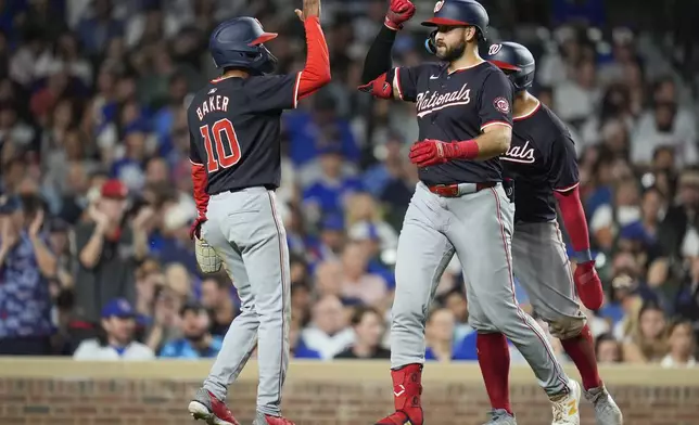 Washington Nationals' Joey Gallo, front right, high-fives Darren Baker(10) after hitting a three-run home run during the sixth inning of a baseball game against the Chicago Cubs, Thursday, Sept. 19, 2024, in Chicago. (AP Photo/Erin Hooley)