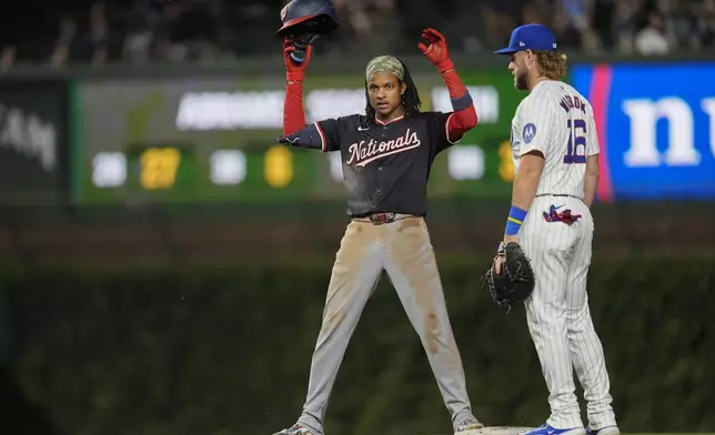 Washington Nationals' CJ Abrams, left, does a little dance toward his dugout next to Chicago Cubs first baseman Patrick Wisdom after Abrams hit a double during the third inning of a baseball game against the Chicago Cubs, Thursday, Sept. 19, 2024, in Chicago. (AP Photo/Erin Hooley)