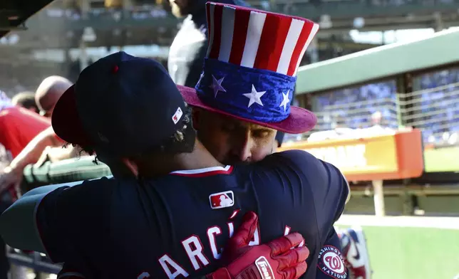 Washington Nationals' Joey Gallo, right, celebrates with teammate Luis Garcia Jr., in the dugout after hitting a three-run home run during the sixth inning of a baseball game against the Chicago Cubs in Chicago, Saturday, Sept. 21, 2024. (AP Photo/Paul Beaty)