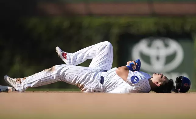 Chicago Cubs Seiya Suzuki lays in the ground after being hit by Washington Nationals catcher Drew Millas' throw to second as Suzuki stole the base during the eighth inning of a baseball game Friday, Sept. 20, 2024, in Chicago. (AP Photo/Charles Rex Arbogast)