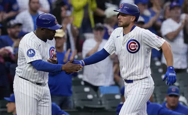 Chicago Cubs' Michael Busch, right, celebrates with third base coach Willie Harris, left, as he rounds the bases after hitting a solo home run during the fourth inning of a baseball game against the Washington Nationals in Chicago, Sunday, Sept. 22, 2024. (AP Photo/Nam Y. Huh)