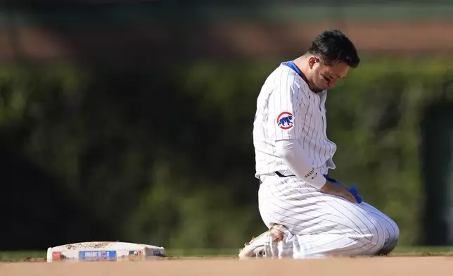 Chicago Cubs Seiya Suzuki sits on the ground after being hit by Washington Nationals catcher Drew Millas' throw to second as Suzuki stole the base during the eighth inning of a baseball game Friday, Sept. 20, 2024, in Chicago. (AP Photo/Charles Rex Arbogast)