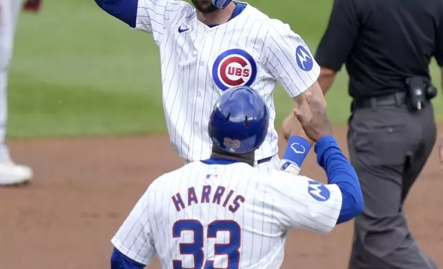 Chicago Cubs' Dansby Swanson celebrates his home run off Washington Nationals starting pitcher Trevor Williams with third base coach Willie Harris, during the first inning of a baseball game Friday, Sept. 20, 2024, in Chicago. (AP Photo/Charles Rex Arbogast)