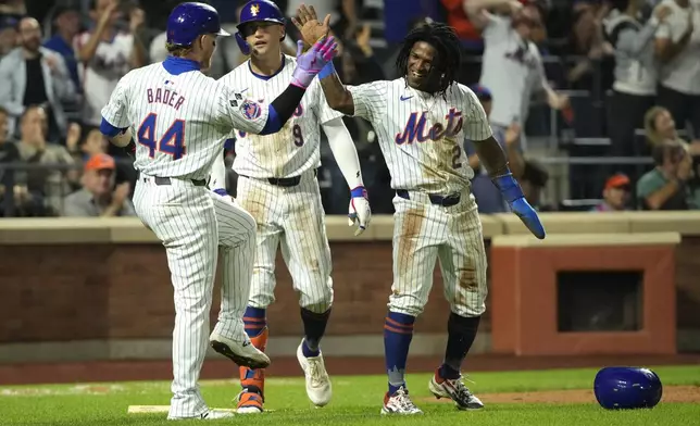 New York Mets' Harrison Bader, left, Brandon Nimmo, center, and Luisangel Acuna, right, react after Bader and Acuna scored on a single hit by Starling Marte during the fourth inning of a baseball game against the Washington Nationals, Wednesday, Sept. 18, 2024, in New York. (AP Photo/Pamela Smith)