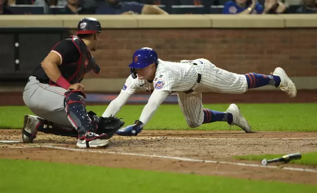 New York Mets' Brandon Nimmo, right, slides to home plate to score on a double hit by Tyrone Taylor as Washington Nationals catcher Drew Millas, left, attempts to ground him out during the fourth inning of a baseball game, Wednesday, Sept. 18, 2024, in New York. (AP Photo/Pamela Smith)