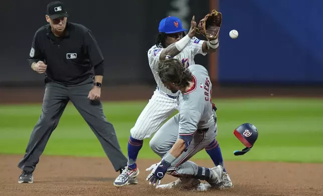 Washington Nationals' Dylan Crews slides past New York Mets' Luisangel Acuna for a double during the second inning of a baseball game, Tuesday, Sept. 17, 2024, in New York. (AP Photo/Frank Franklin II)