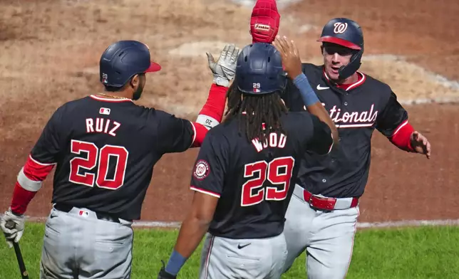 Washington Nationals' Jacob Young, right, celebrates with James Wood (29) and Keibert Ruiz (20) after scoring the second of two runs on a double by Ildemaro Vargas off Pittsburgh Pirates relief pitcher Aroldis Chapman during the ninth inning of the second baseball game of a doubleheader in Pittsburgh, Saturday, Sept. 7, 2024. (AP Photo/Gene J. Puskar)