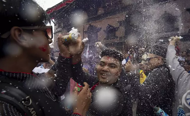 Devotees use foam spray as they dance during Indra Jatra, a festival that marks the end of the rainy season in Kathmandu, Nepal, Tuesday, Sept. 17, 2024. (AP Photo/Niranjan Shrestha)