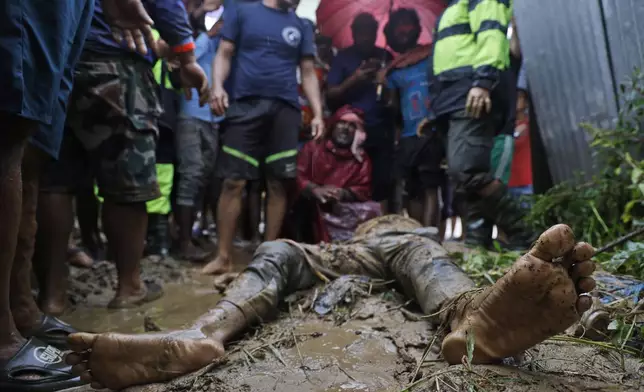 EDS NOTE: GRAPHIC CONTENT - People, including relatives, stand by the body of Nandu Sah, 34, a scrap dealer, who died after the shed he was sleeping under was flooded due to heavy rains, on the outskirts of Kathmandu, Nepal, Saturday, Sept. 28, 2024. (AP Photo/Gopen Rai)