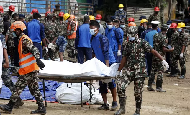 Rescue personnel transport the dead body of a victim who was trapped under a landslide caused by heavy rains in Kathmandu, Nepal, Sunday, Sept. 29, 2024. (AP Photo/Sujan Gurung)