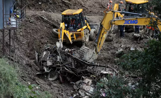 Earthmovers remove mangled automobile debris from a landslide caused by heavy rains in Kathmandu, Nepal, Sunday, Sept. 29, 2024. (AP Photo/Sujan Gurung)