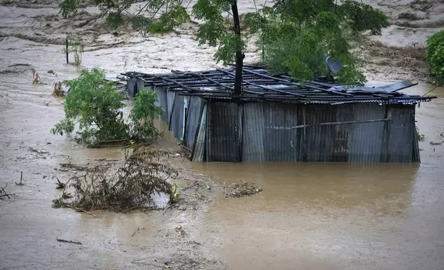 A tin shed lies partially submerged at the edge of the Bagmati River in spate after heavy rains in Kathmandu, Nepal, Saturday, Sept. 28, 2024. (AP Photo/Gopen Rai)