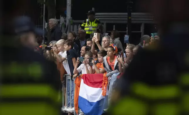 Dutch police, foreground and background, monitor the crowd waiting for Dutch King Willem-Alexander and Queen Maxima to arrive, prior to the King outlining the new government's policy plans and budget for the coming year in The Hague, Netherlands, Tuesday, Sept. 17, 2024. (AP Photo/Peter Dejong)