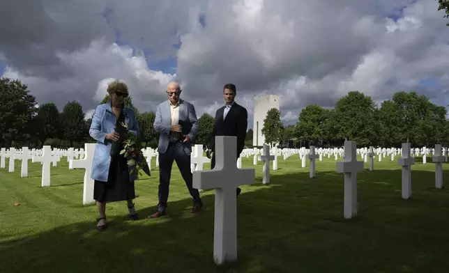 Eighty years after the liberation of the south of the Netherlands, Scott Taylor, right, Ton Hermes, center, and Maria Kleijnen stand next to the grave of Scott's grandfather Second Lt. Royce Taylor, a bombardier with the 527 Bomb Squadron, at the Netherlands American Cemetery in Margraten, southern Netherlands, on Wednesday, Sept. 11, 2024. (AP Photo/Peter Dejong)