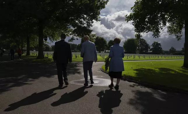 Eighty years after the liberation of the south of the Netherlands, Scott Taylor, left, Ton Hermes, center, and Maria Kleijnen walk to the grave of Scott's grandfather Second Lt. Royce Taylor, a bombardier with the 527 Bomb Squadron, at the Netherlands American Cemetery in Margraten, southern Netherlands, on Wednesday, Sept. 11, 2024. (AP Photo/Peter Dejong)