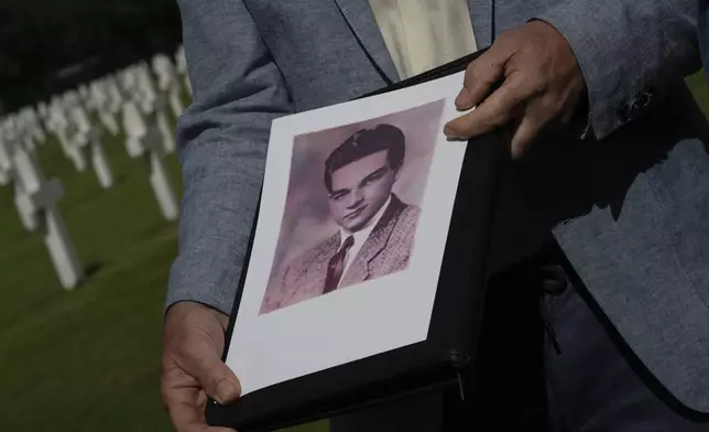 Eighty years after the liberation of the south of the Netherlands Ton Hermes holds a picture of Second Lt. Royce Taylor, a bombardier with the 527 Bomb Squadron, next to his grave at the Netherlands American Cemetery in Margraten, southern Netherlands, on Wednesday, Sept. 11, 2024. (AP Photo/Peter Dejong)