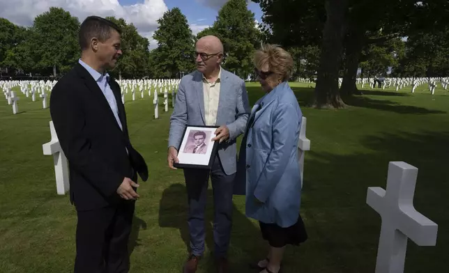 Eighty years after the liberation of the south of the Netherlands, Scott Taylor, left, Ton Hermes, center, and Maria Kleijnen, left, talk as they look at a picture of Scott's grandfather Second Lt. Royce Taylor, a bombardier with the 527 Bomb Squadron, at the Netherlands American Cemetery in Margraten, southern Netherlands, on Wednesday, Sept. 11, 2024. (AP Photo/Peter Dejong)