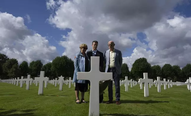 Eighty years after the liberation of the south of the Netherlands, Scott Taylor, center, Ton Hermes and Maria Kleijnen stand next to the grave of Scott's grandfather Second Lt. Royce Taylor, a bombardier with the 527 Bomb Squadron, at the Netherlands American Cemetery in Margraten, southern Netherlands, on Wednesday, Sept. 11, 2024. (AP Photo/Peter Dejong)