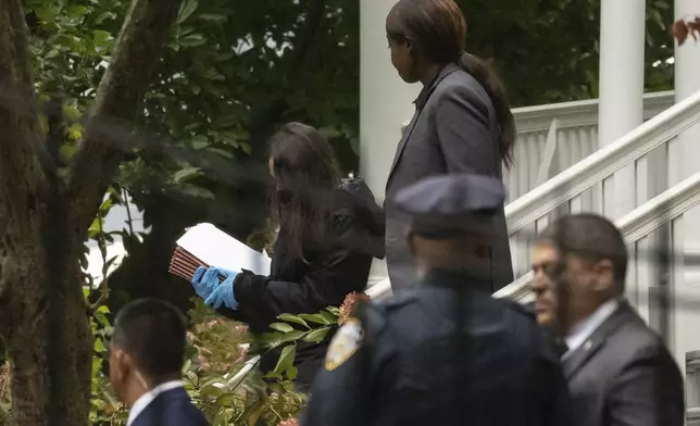 A person wearing gloves and carrying Manila folders exits Gracie Mansion, the official residence of New York City Mayor Eric Adams, Thursday, Sept. 26, 2024, in New York. (AP Photo/Yuki Iwamura)