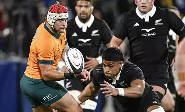 Australia's Fraser McReight, left, passes the ball as New Zealand's Tupou Vaa'i makes a tackle during their Rugby Championship match between the All Blacks and the Wallabies in Wellington, New Zealand, Saturday, Sept. 28, 2024.(Andrew Cornaga/Photosport via AP)