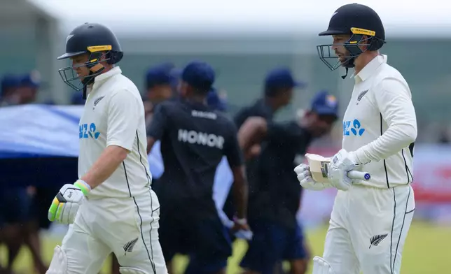 New Zealand's Tom Latham, left, and teammate Devon Conway leave the ground after rain disrupted play on the second day of the first cricket test match between New Zealand and Sri Lanka in Galle, Sri Lanka, Thursday, Sept. 19, 2024. (AP Photo/Viraj Kothalawala)