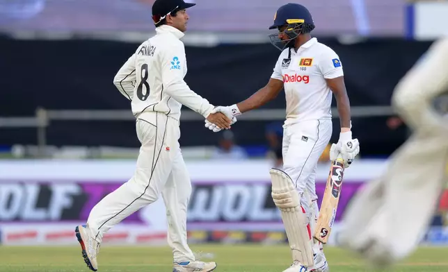 New Zealand's Rachin Ravindra, left, runs up to Sri Lanka's Kamindu Mendis to shake his hand as the latter leaves the field after losing his wicket on the first day of the first cricket test match between New Zealand and Sri Lanka in Galle, Sri Lanka, Wednesday, Sept. 18, 2024. (AP Photo/Viraj Kothalawala)