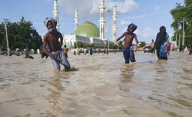 People walk through floodwaters following a dam collapse in Maiduguri, Nigeria, Tuesday Sept 10, 2024. (AP Photos/ Joshua Olatunji)