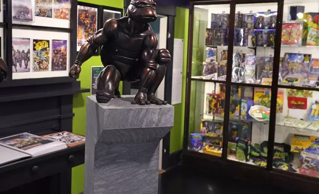 A bronze sculpture of the Teenage Mutant Ninja Turtle character "Raphael" is displayed along with comic books and memorabilia in a permanent collection at the Woodman Museum, Thursday, Sept. 5, 2024, in Dover, N.H. (AP Photo/Charles Krupa)