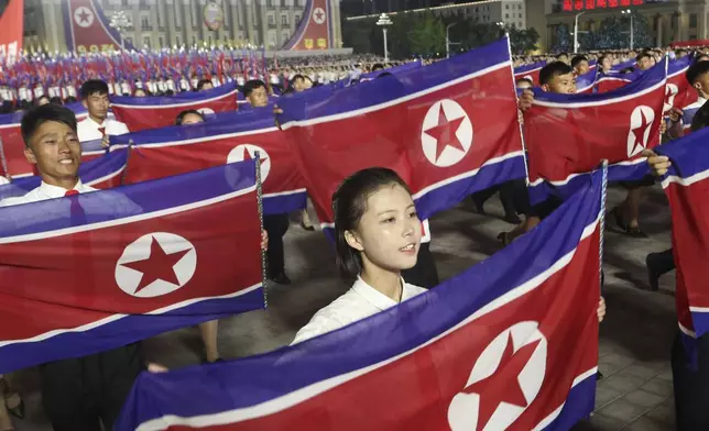 North Koreans march with their nationa flag as they celebrate the country's 76th founding anniversary at Kim Il Sung Square in Pyongyang, North Korea Sunday, Sept. 8, 2024. (AP Photo/Jon Chol Jin)