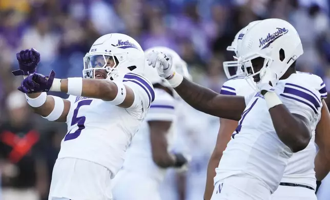 Northwestern linebacker Kenny Soares Jr. (5) and defensive lineman Anto Saka, right, celebrate a sack of Washington quarterback Will Rogers during the first half of an NCAA college football game Saturday, Sept. 21, 2024, in Seattle. (AP Photo/Lindsey Wasson)