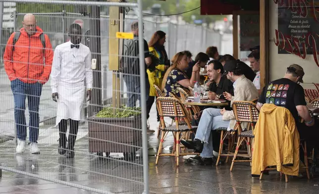 FILE - Patrons sit outside a restaurant behind some remaining security barriers on a street along the River Seine, now opened to foot traffic after Friday's opening ceremony at the 2024 Summer Olympics, July 27, 2024, in Paris, France. (AP Photo/Rebecca Blackwell, File)