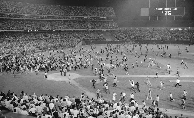 FILE - Fans pour onto the field at the Oakland Coliseum after the Oakland A's beat the Los Angeles Dodgers 3-2 and won their third straight World Series, Oct. 17, 1974, in Oakland. (AP Photo, File)