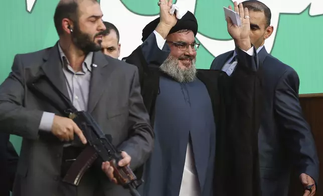 FILE - Hezbollah leader Hassan Nasrallah, center, escorted by his bodyguards, waves to a crowd of tens of thousands of supporters during a rally in Beirut's southern suburbs, Monday Sept. 17, 2012. (AP Photo/Hussein Malla, File)