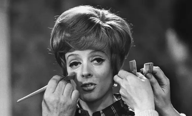 FILE - Make up and hair artists add the finishing touches to British actress Maggie Smith before she faces the camera with Peter Ustinov in the comedy 'Hot Millions' being filmed at Elstree Studios, England, Jan. 12, 1968. Smith has died aged 89. (AP Photo/Bob Dear, File)