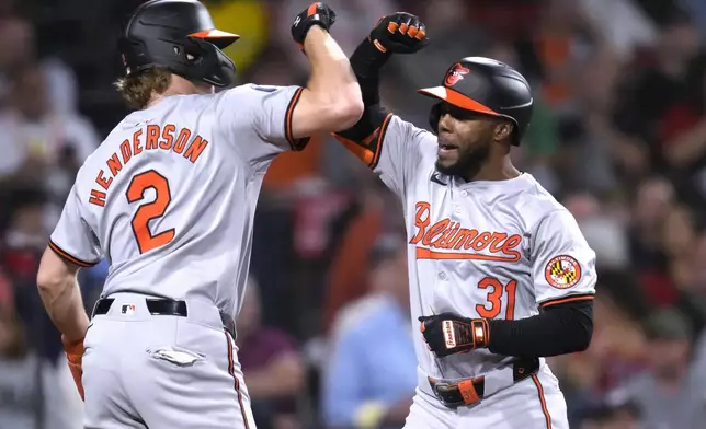 Baltimore Orioles' Cedric Mullins, right, is congratulated by Gunnar Henderson (2) after his two-run home run during the third inning of a baseball game against the Boston Red Sox at Fenway Park, Tuesday, Sept. 10, 2024, in Boston. (AP Photo/Charles Krupa)