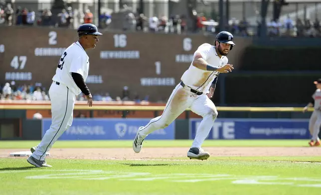 Detroit Tigers third base coach Joey Cora, left, watches as Matt Vierling, right, runs to score on an RBI single by Colt Keith against the Baltimore Orioles in the sixth inning of a baseball game, Sunday, Sept. 15, 2024, in Detroit. (AP Photo/Jose Juarez)