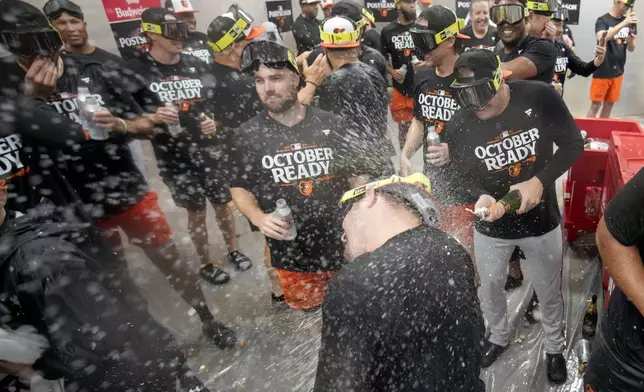 Baltimore Orioles' players celebrate after clinching a playoff berth by defeating the New York Yankees in baseball game, Tuesday, Sept. 24, 2024, in New York. (AP Photo/Bryan Woolston)