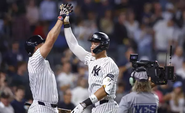 New York Yankees' Aaron Judge, center, celebrates with Giancarlo Stanton, left, after hitting a home run against the Baltimore Orioles during the seventh inning of a baseball game, Thursday, Sept. 26, 2024, in New York. (AP Photo/Noah K. Murray)