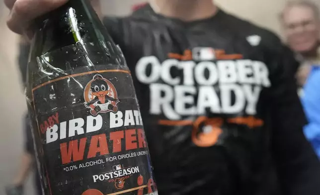 Baltimore Orioles' Jackson Holliday holds a bottle of a nonalcoholic beverage during post-game celebrations after the team clinched a playoff berth by defeating the New York Yankees in baseball game, Tuesday, Sept. 24, 2024, in New York. Holliday is the only member of the Orioles not of legal drinking age. (AP Photo/Bryan Woolston)