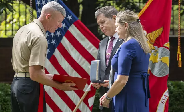 Commandant of the Marine Corps Gen. Eric Smith, left, presents a the Navy and Marine Corps Medal and citation to the parents of Cpl. Spencer Collart, Alexia and Bart Collart during a ceremony on Monday, Sept. 16, 2024 in Washington. (AP Photo/Kevin Wolf)