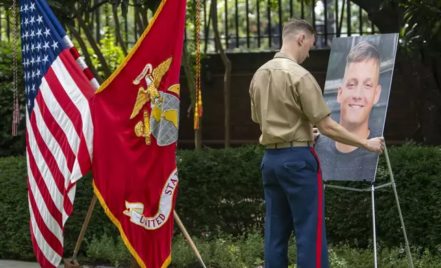 A marine places a photo of Cpl. Spencer Collart on an easel before a ceremony where he is posthumously awarded the Navy and Marine Corps medal on Monday, Sept. 16, 2024 in Washington. Cpl. (AP Photo/Kevin Wolf)