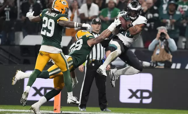 Philadelphia Eagles running back Saquon Barkley (26) scores past Green Bay Packers linebacker Isaiah McDuffie (58) during the first half of an NFL football game, Friday, Sept. 6, 2024, at the Neo Quimica Arena in Sao Paulo. (AP Photo/Doug Benc)